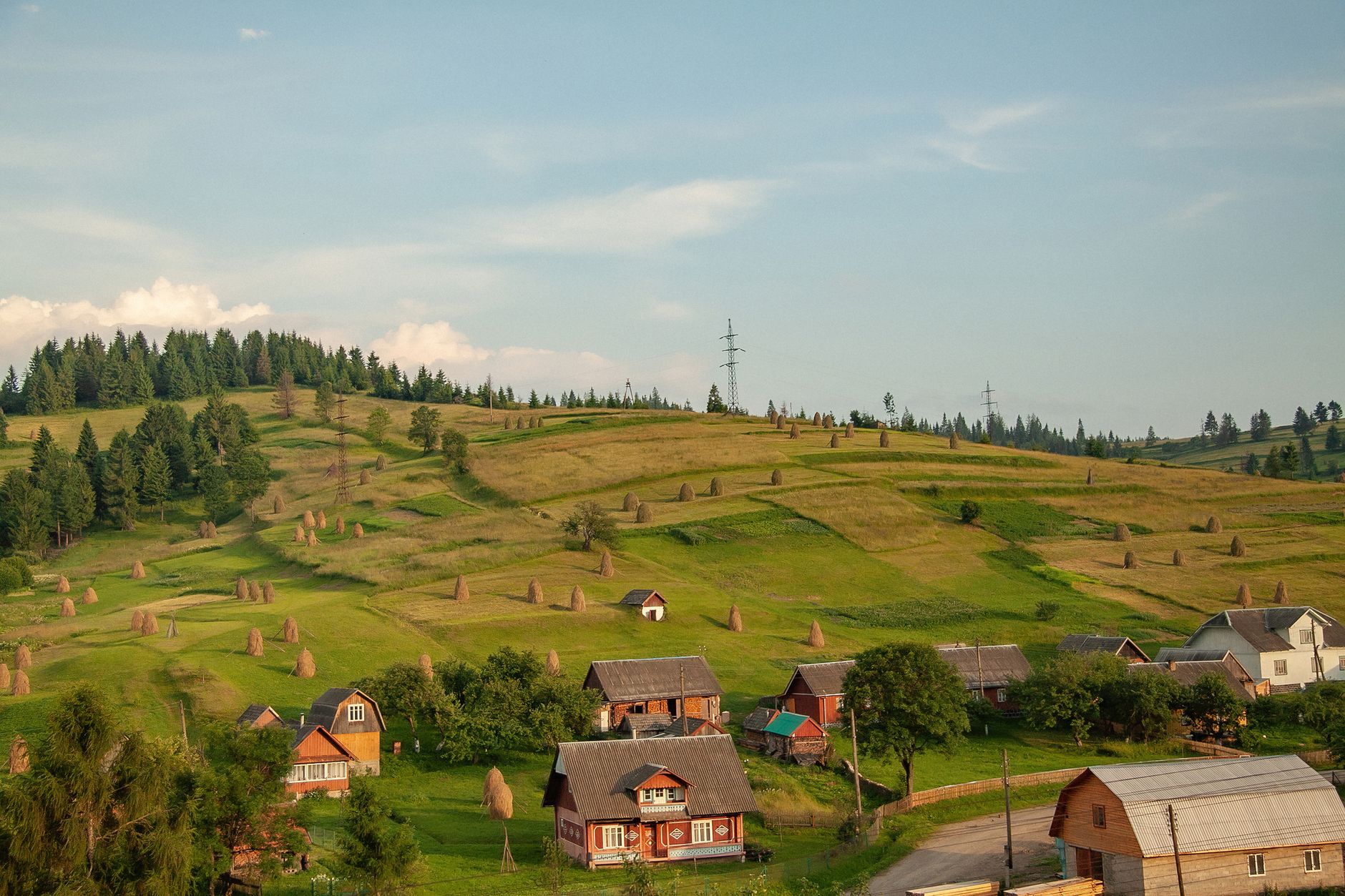 A Romanian village spread over hills with meadows and pastures under a covered sky