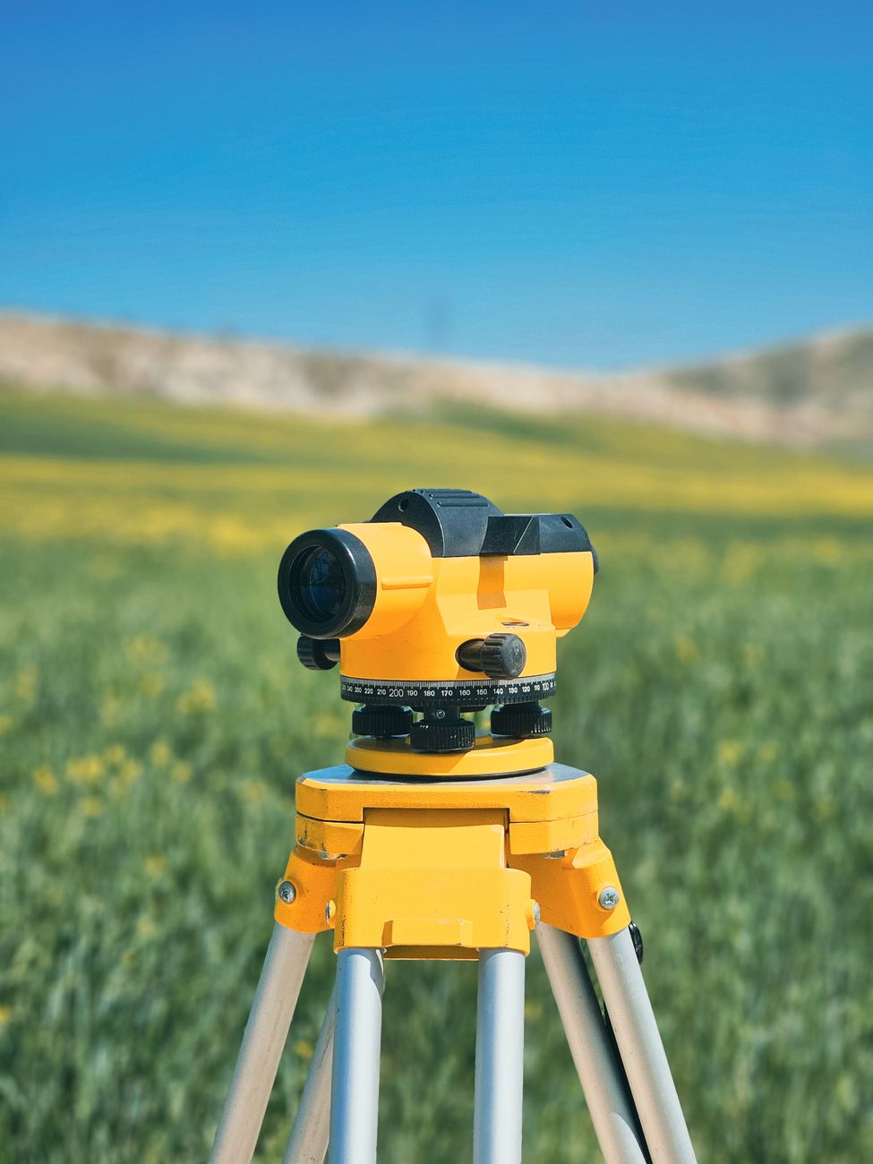 Surveyor in the field with a theodolite on a tripod, measuring open ground